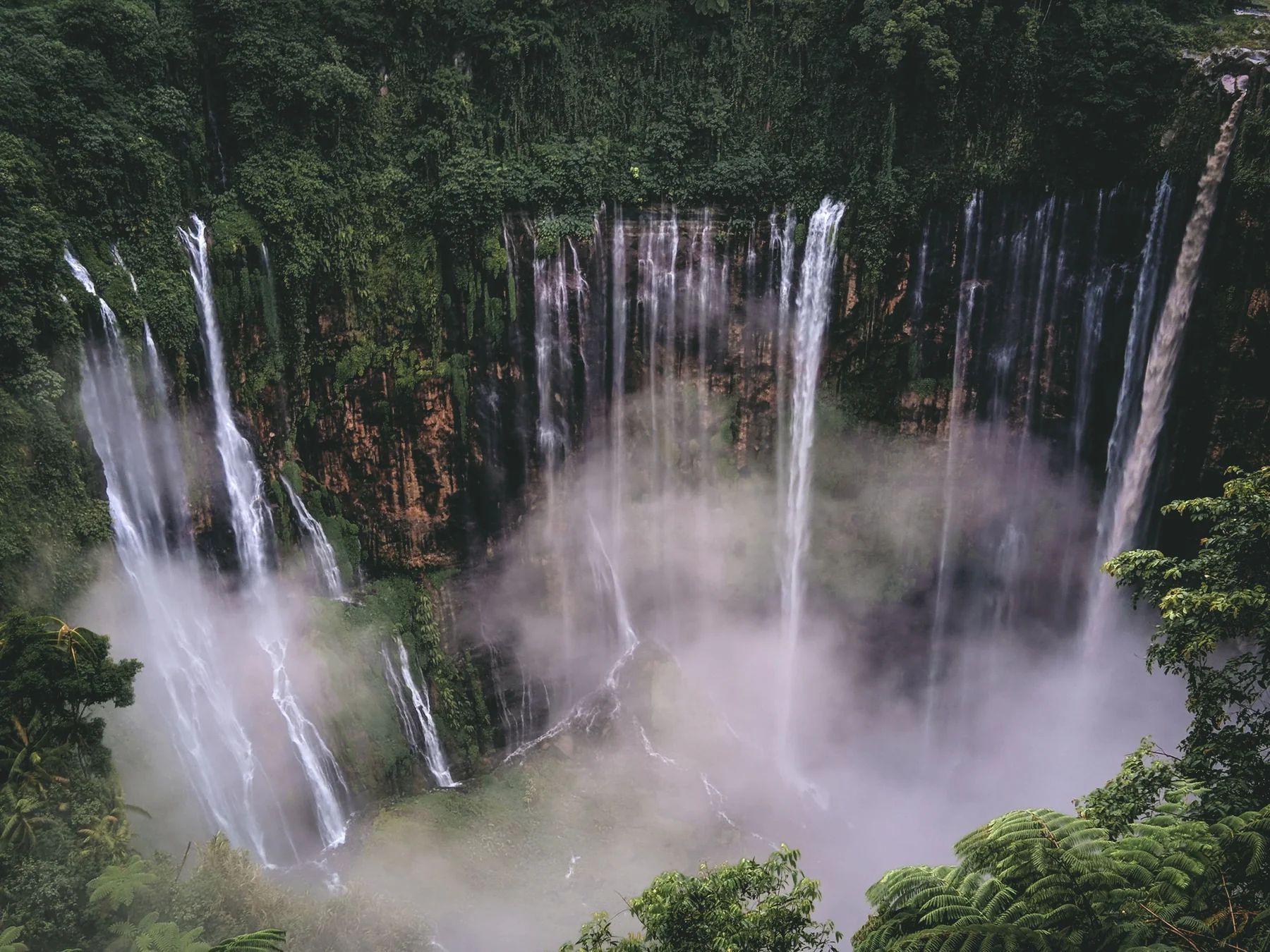 Tirai Air Terjun Tumpak Sewu dilihat dari udara di antara tebing hijau